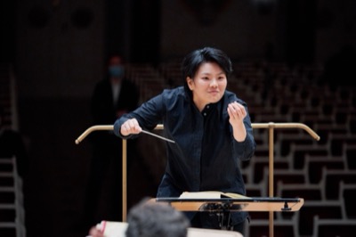Rira Kim at the podium, smiling while conducting